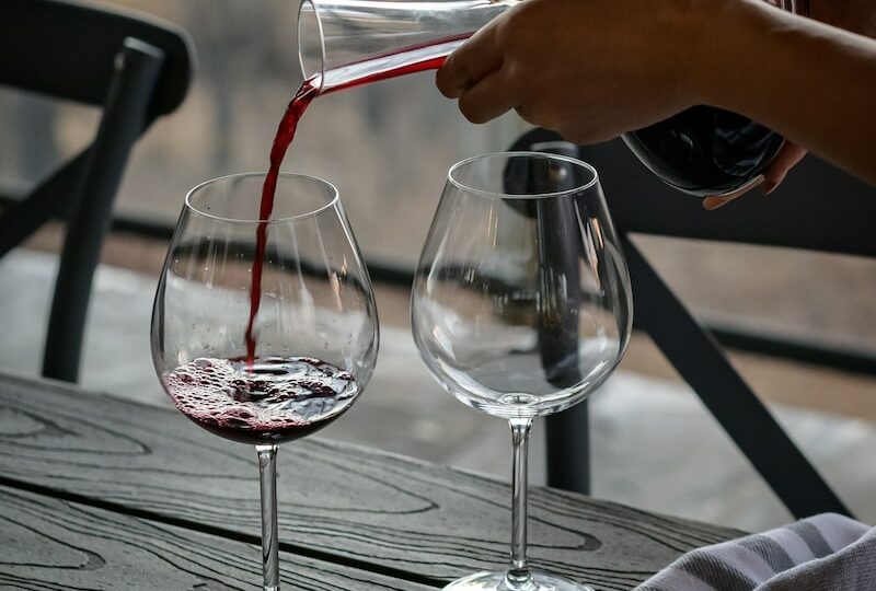person pouring wine from decanter on wineglass